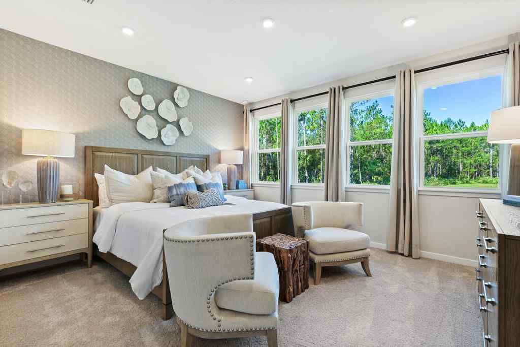 A bedroom with a bed and chairs.