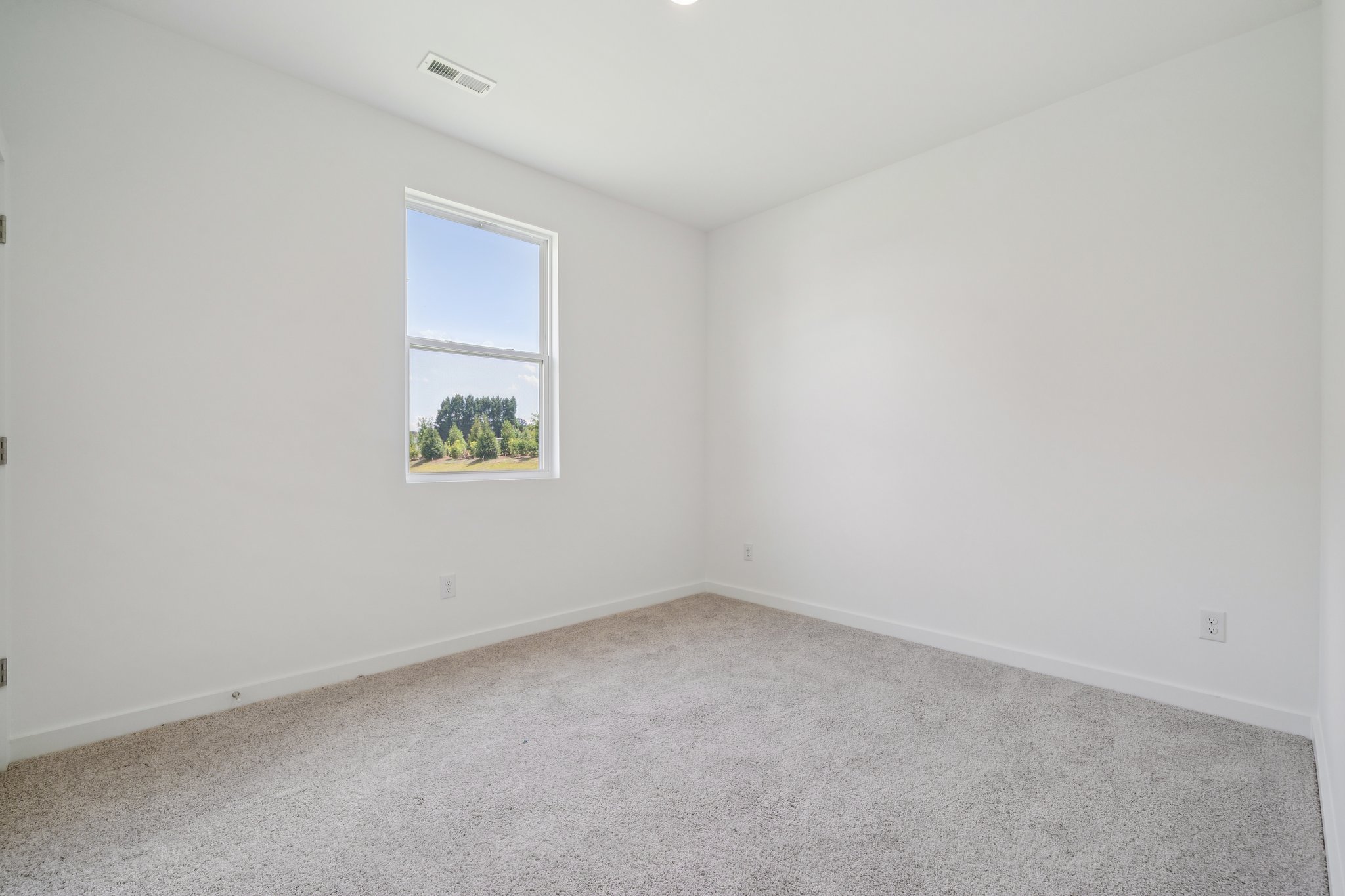 A room with a window and a white wall.