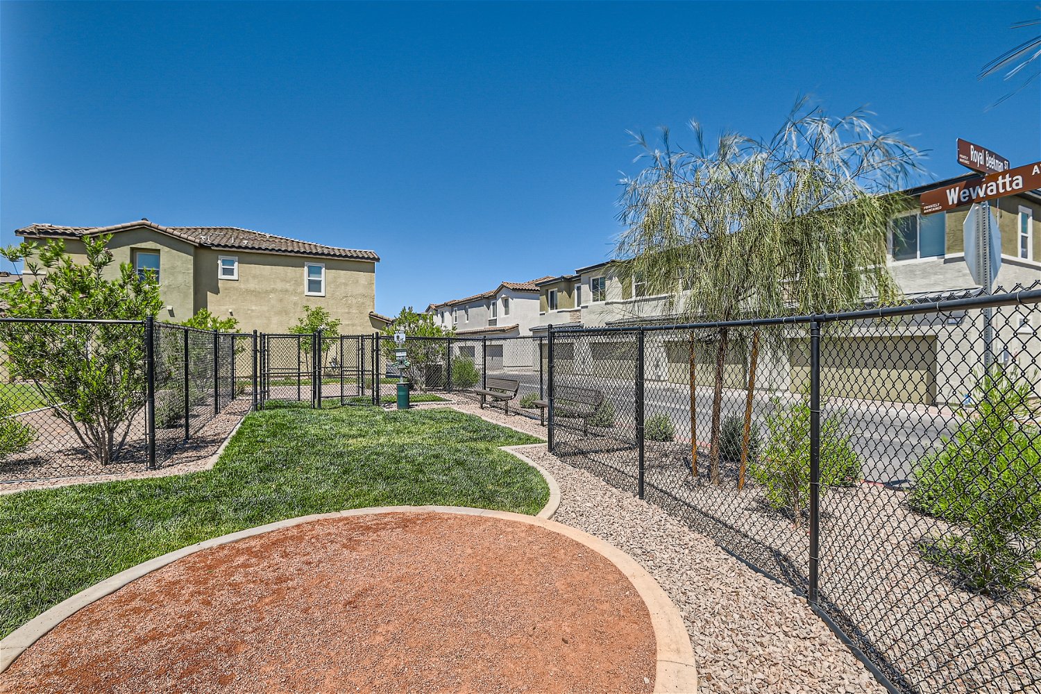 A fenced in yard with a brick path and a building.