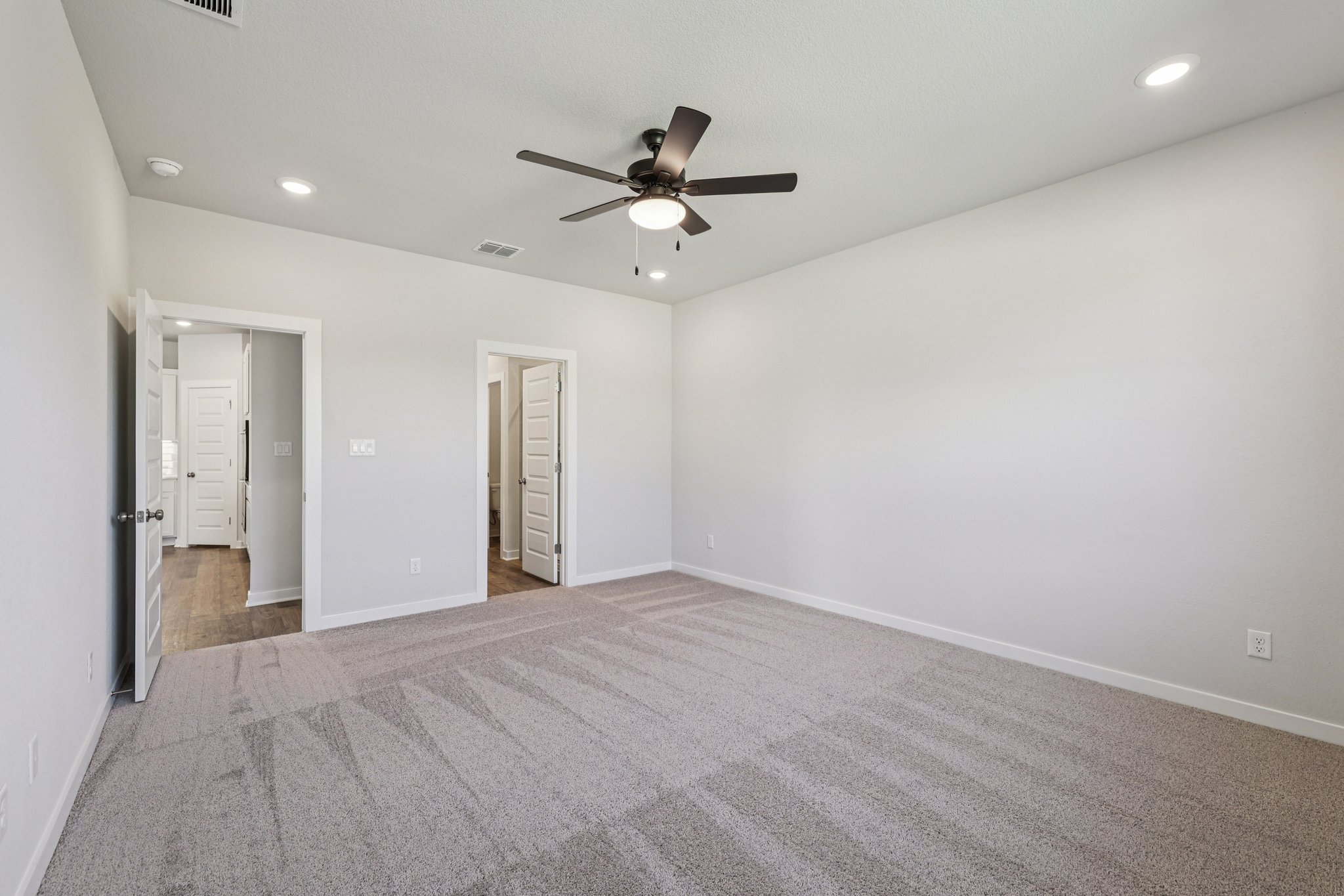 A room with a ceiling fan and a carpet.