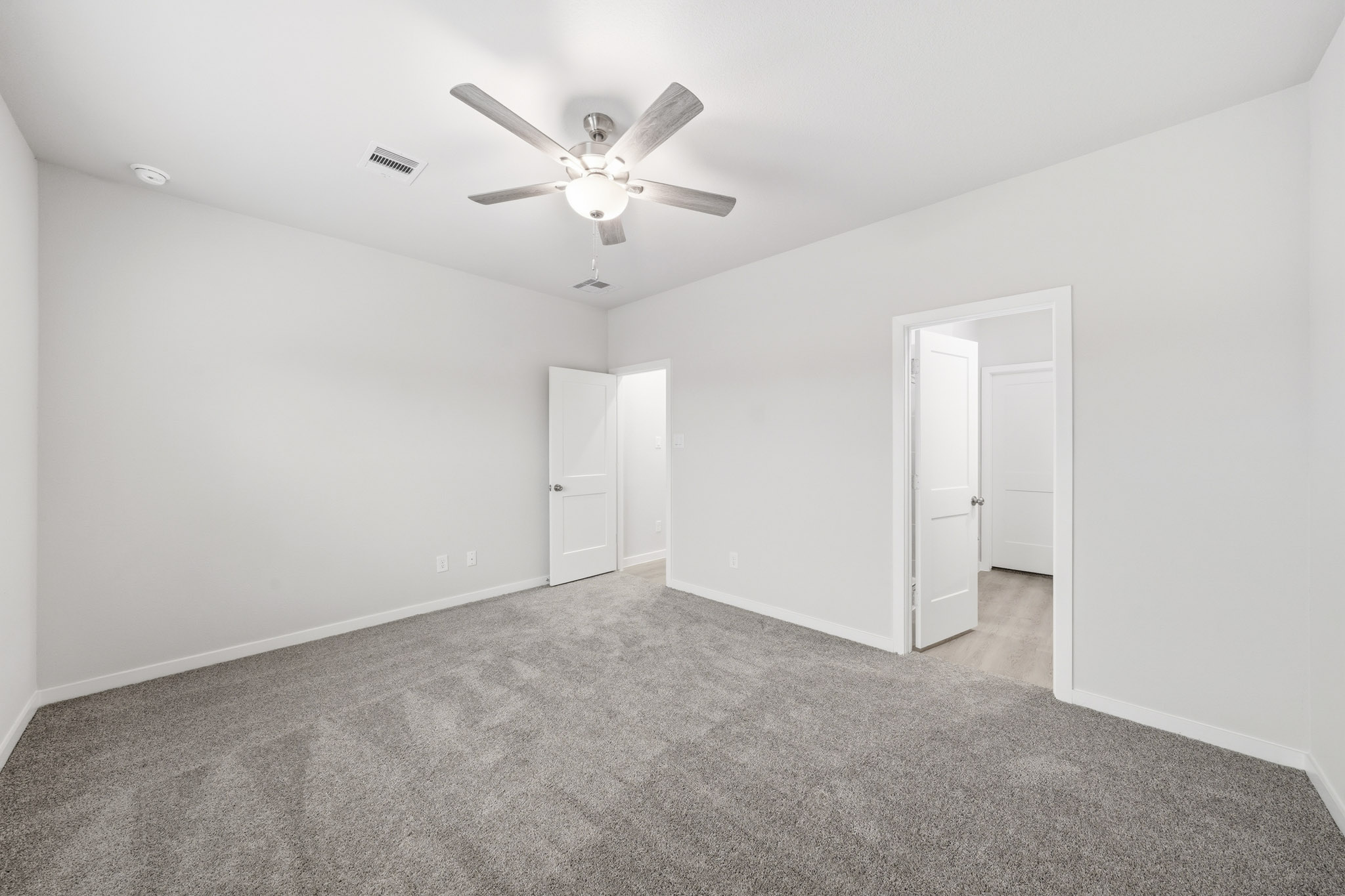 A room with a ceiling fan and white doors.