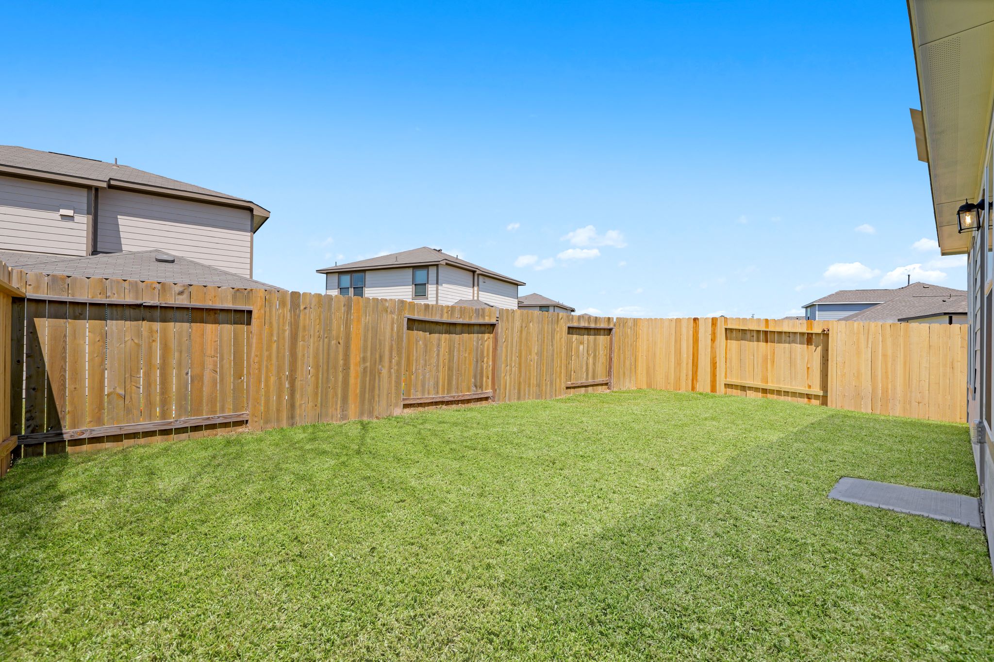 A fenced in yard with a house in the background.