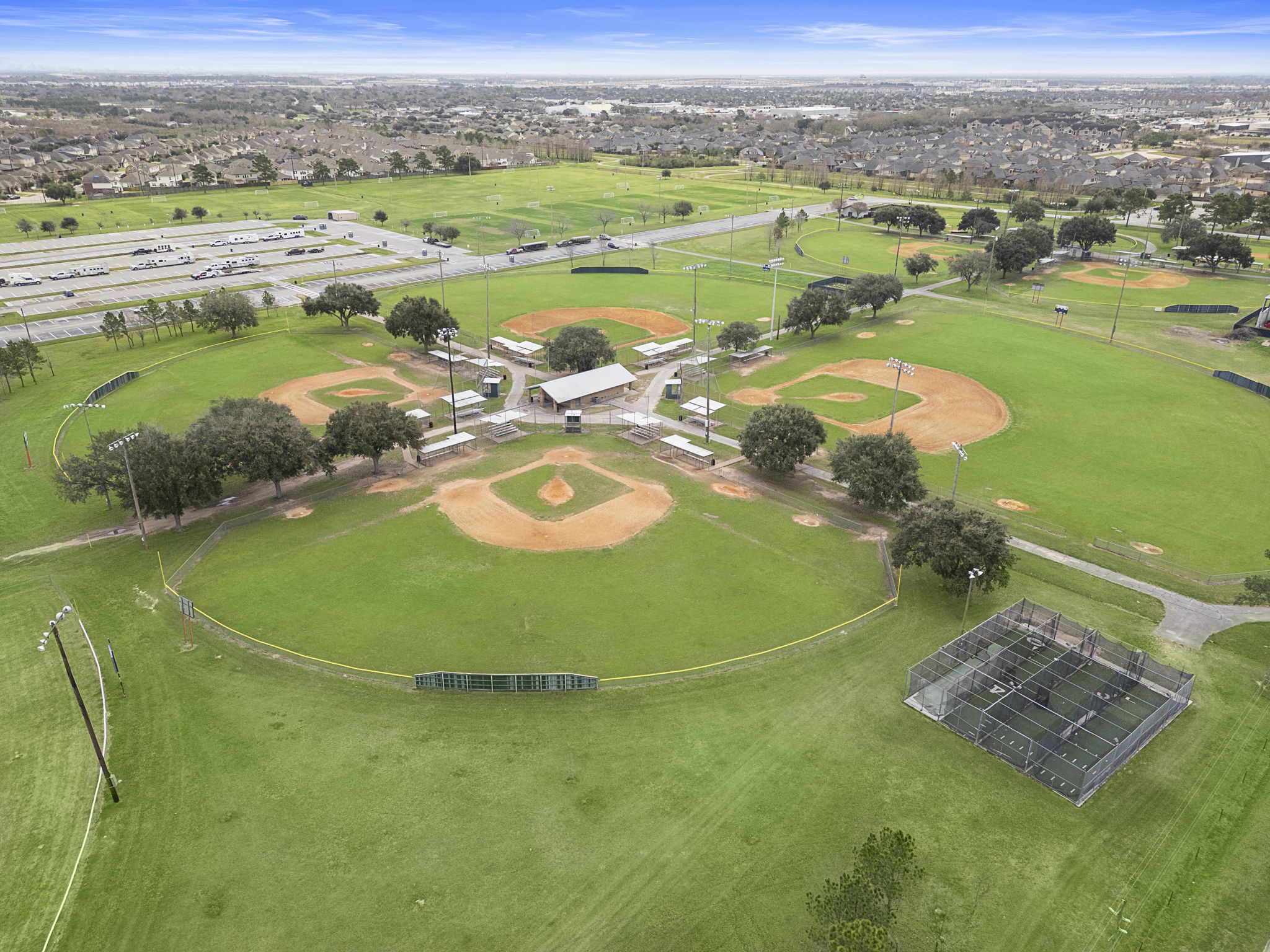 A large green field with buildings and trees.