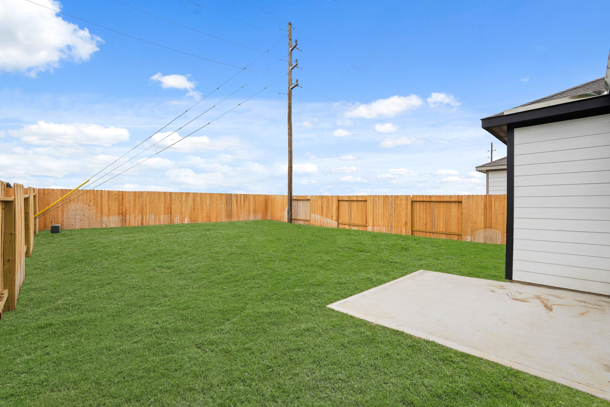 A fenced in yard with a wooden pole and a building.