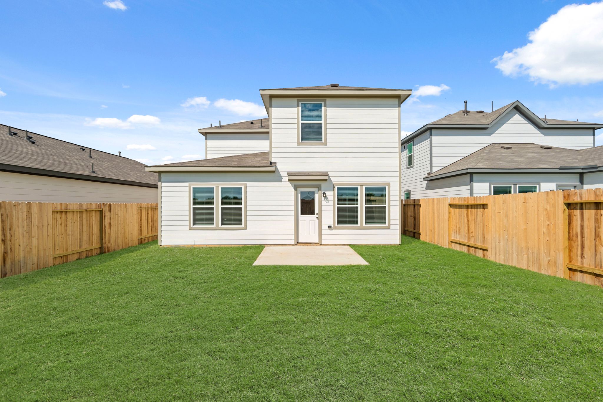 A backyard with a fence and a house.