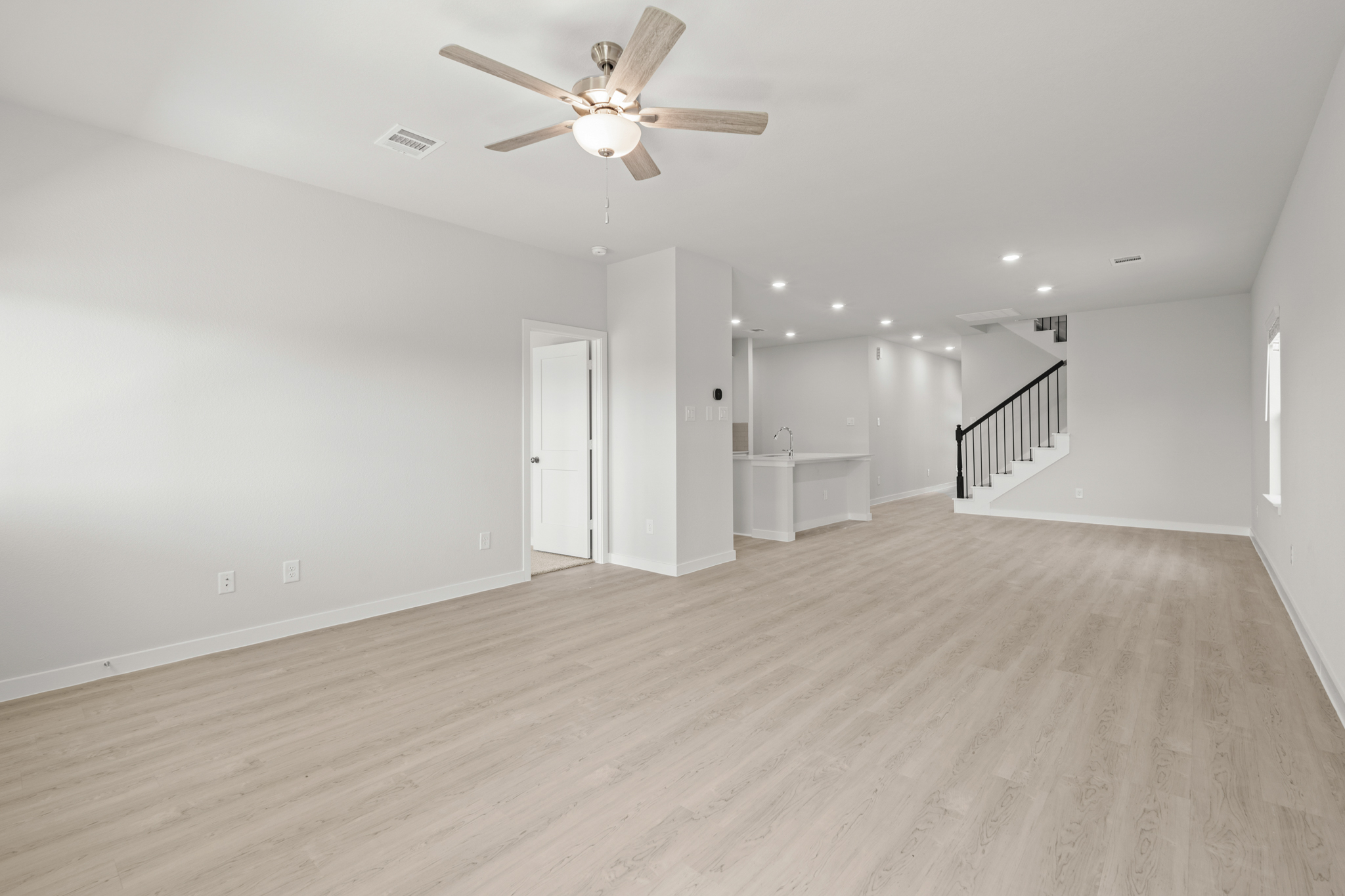 A large empty room with a ceiling fan and a wood floor.