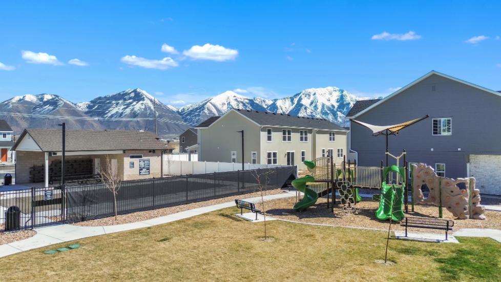 A fenced in yard with buildings and mountains in the background.