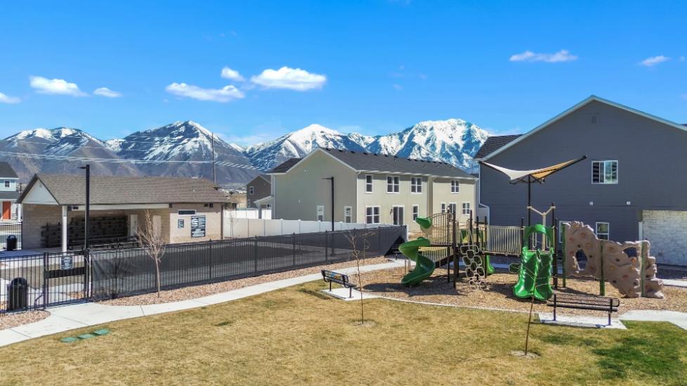 A fenced in yard with houses and mountains in the background.