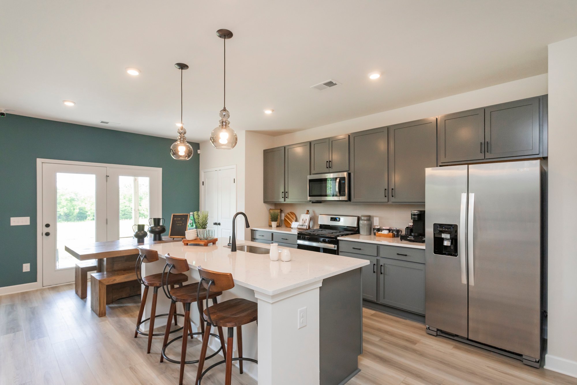 A kitchen with a fridge and stools.