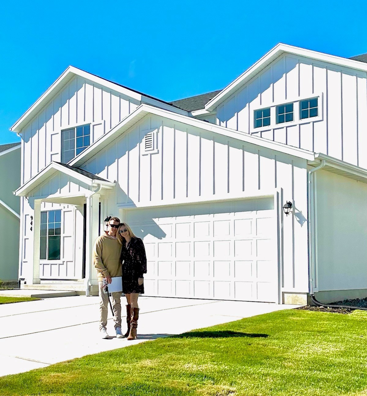 A man and woman kissing in front of a white house.